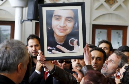 The father of Elvin Bugra Arslan, one of the victim of Sunday's suicide bomb attack, holds up his son's picture during a funeral ceremony in Ankara, Turkey March 15, 2016. REUTERS/Umit Bektas