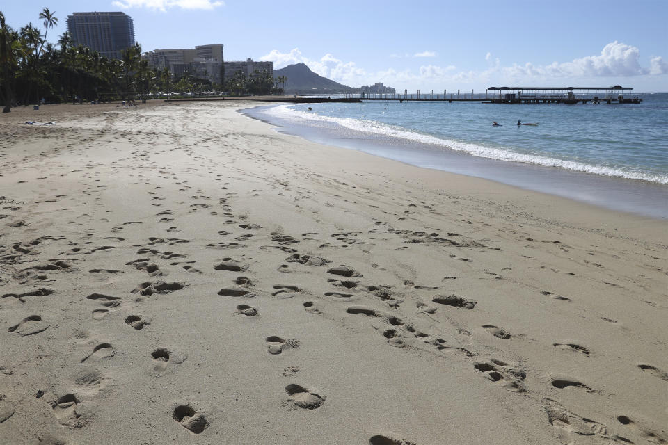 A near empty Waikiki Beach is viewed Thursday, Oct. 15, 2020, in Honolulu. A new pre-travel testing program will allow visitors who test negative for COVID-19 to come to Hawaii and avoid two weeks of mandatory quarantine goes into effect Thursday. The pandemic has caused a devastating downturn on Hawaii's tourism-based economy and many are hoping the testing will help the economy rebound. (AP Photo/Marco Garcia)