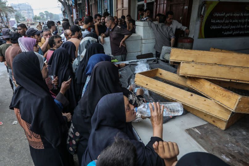 Palestinians wait in front of a bakery shop to meet their daily food needs on Sunday