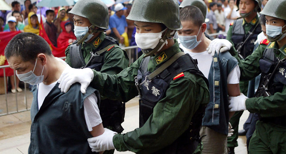 Chinese police wear masks as they escort two convicted drug pedlars for their executions in the eastern city of Hangzhou in 2004. 