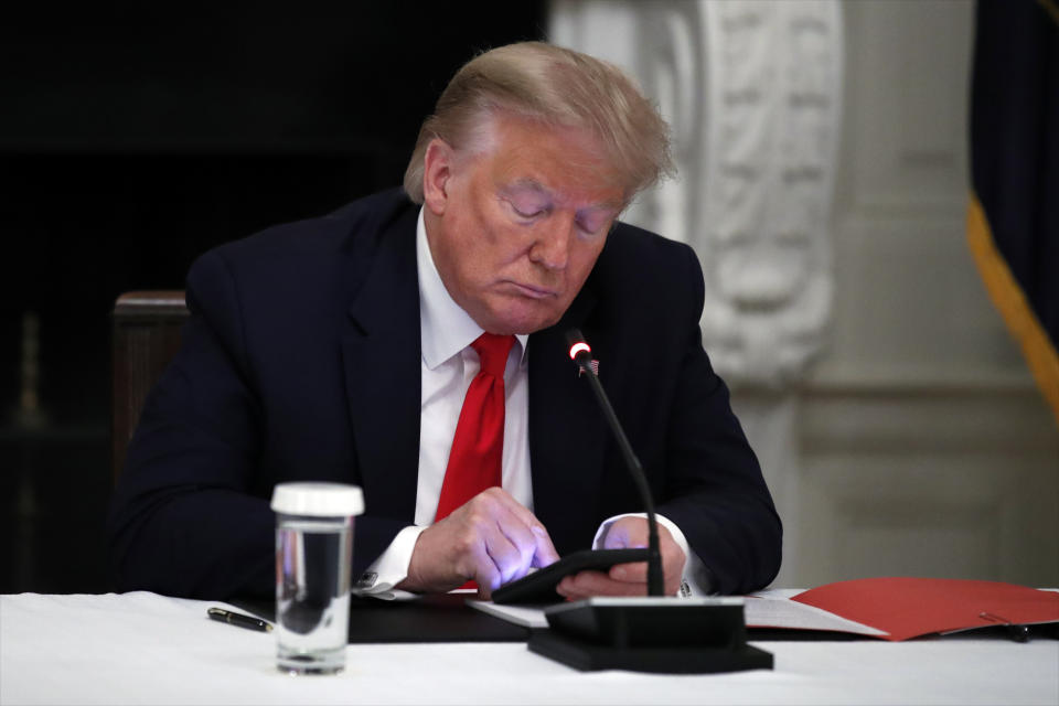 President Trump looks at his phone during a small business roundtable with governors at the White House on June 18, 2020. 