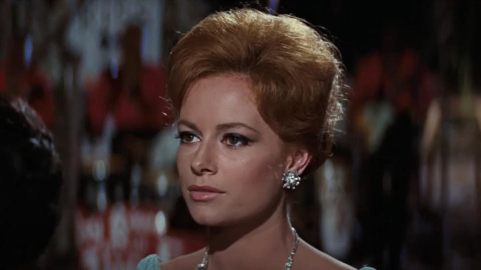 Luciana Paluzzi stands wearing fancy jewelry in a night time scene in Thunderball.