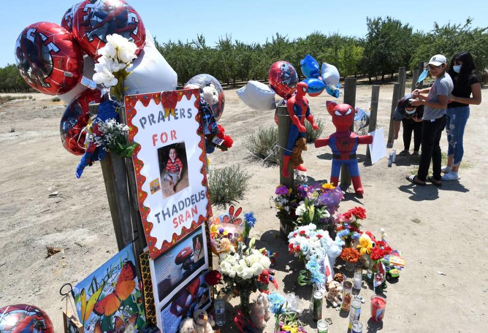 People pay their respects to 2-year-old Thaddeus Sran, Saturday July 25, 2020, at a Road 21 memorial set up near where authorities found remains believed to be the boy’s body were found Thursday, west of Madera. People are leaving toys, candles, flowers and messages.