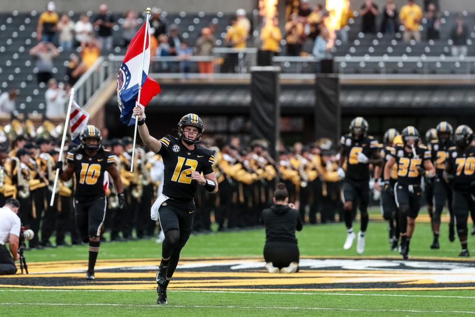 Missouri quarterback Brady Cook (12) carries the state flag prior to a game last season at Faurot Field.