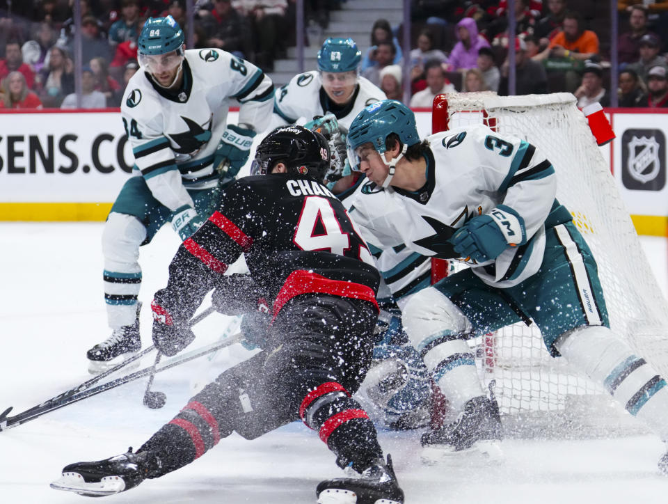 San Jose Sharks defenseman Henry Thrun (3) tries to stop Ottawa Senators center Rourke Chartier (49) from wrapping the puck around the net during the second period of an NHL hockey game, Saturday, Jan. 13, 2024 in Ottawa, Ontario. (Sean Kilpatrick/The Canadian Press via AP)
