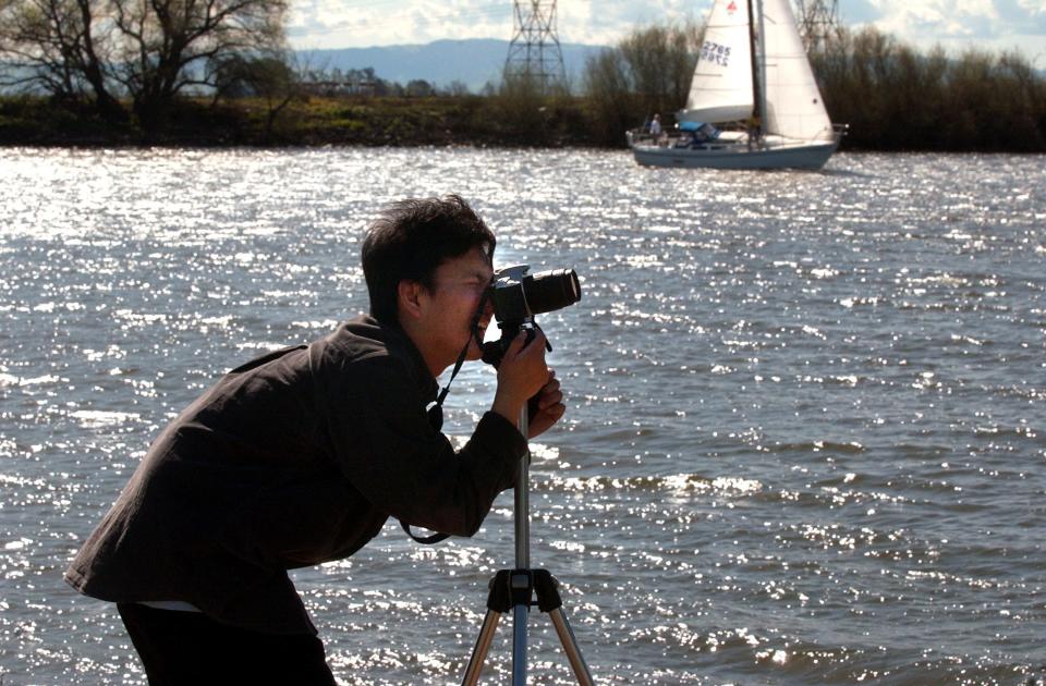 Yi-Fang Chang takes advantage of the sunny day to take some scenic photographs at Buckley Cove Park in Stockton for a photography class at school on Mar. 17, 2003.