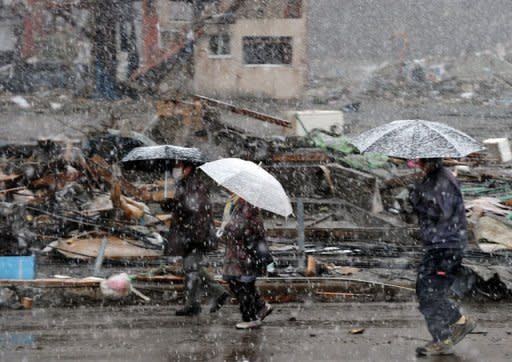 Survivors walk in the snow after checking on what was left of their properties in the tsunami devastated Kamaishi city, Iwate prefecture. Aside from the nuclear threat, the full scale of the quake and tsunami disaster was becoming clear as more details emerged of the staggering death and devastation in the worst-hit northeast