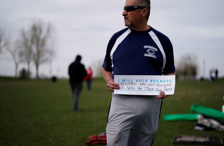 Rick Martinez holds a sign as teens kick off a voter registration rally, a day ahead of the 19th anniversary of the massacre at Columbine High School, in Littleton, Colorado, U.S., April 19, 2018. REUTERS/Rick Wilking