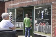 Customers wait in line outside of Steve's Barber Shop in Lee, Mass., Tuesday, May 26, 2020. Barber shops are among the businesses allowed to open in Massachusetts with restrictions as part of phase one of the state reopening plan.(Ben Garver/The Berkshire Eagle via AP)