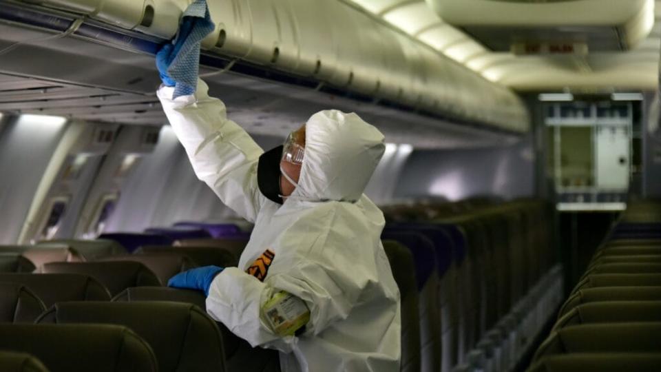 A worker wearing personal protective equipment cleans the passengers cabin of an airplane. In July, a Texas woman died on an airplane before its flight due to complications from COVID-19. (Photo by Guillermo Legaria/Getty Images)