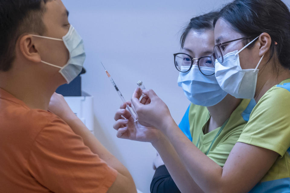 FILE - In this Feb. 23, 2021, file photo, health workers look at a vial and a syringe while administering a dose of the Sinovac Biotech COVID-19 vaccine at a community vaccination center in Hong Kong. Hong Kong's sudden suspension of a COVID-19 vaccine developed by Pfizer and BioNTech is another blow to a vaccination program already struggling against a wall of public distrust. Hong Kong on Wednesday, March 24, 2021, suspended use of the Pfizer vaccine, distributed by Chinese pharmaceutical firm Fosun Pharma, after defective packaging such as loose vial lids and cracks on bottles were found in one of two batches of the vaccine. (Paul Yeung/Pool Photo via AP, File)