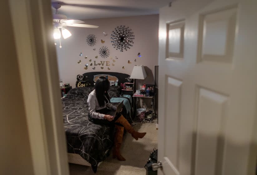 LAKE ELSINORE, CA - DECEMBER 14, 2022: Venezuelan asylum seeker Lisseth, 45, works on her computer in her bedroom on December 14, 2022 in Lake Elsinore, California. She was sponsored by a U.S. citizen to come to the United States. ***PLEASE DO NOT LIGHTEN PHOTO. THE WOMAN MUST REMAIN IN SHADOW AND CAN'T BE IDENTIFIED FOR HER SAFETY**(Gina Ferazzi / Los Angeles Times)