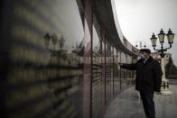 Fazil Melikov, 71, shows the names of his friends who were killed during a fighting with Armenian forces in the memorial wall at a cemetery in Ganja, Azerbaijan, Sunday, Nov. 29, 2020. Melikov and Ibrahimova used to live in Kalbajar, a region of Azerbaijan that had been under Armenian control since the 1990s. Now that the control over the region was handed back over to Azerbaijan, they say they are eager to return to their hometown after fleeing the region over 26 years ago. (AP Photo/Emrah Gurel)