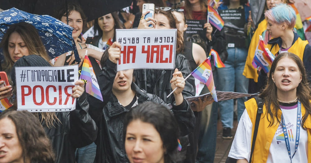 People taking part in a Pride march in Kyiv, Ukraine, carrying signs in Ukranian and Pride flags.