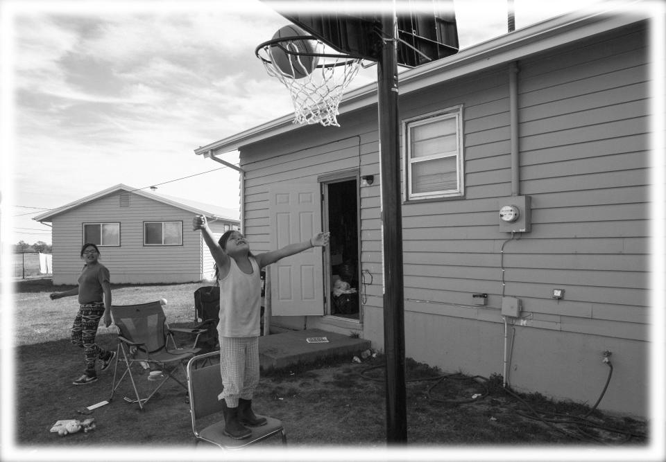 Justice Bull Shows, 13, looks on as Ariya Bull Shows, 6, makes the basket at her home on Rosebud Indian Reservation in South Dakota in 2014. (Photo: Nikki Kahn/The Washington Post via Getty Images; digitally enhanced by Yahoo News)