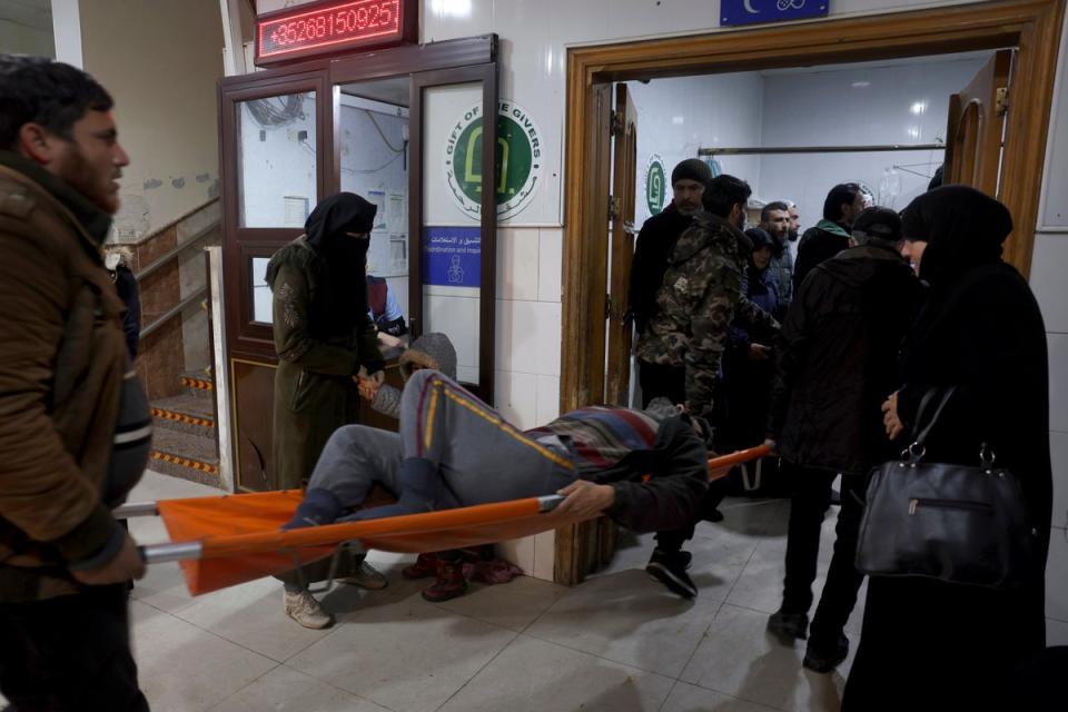 A man injured in the quake is carried into the al-Rahma hospital in Darkush, Idlib province (AP)