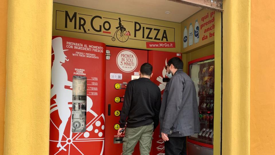 Zwei Männer kaufen sich am Pizza-Automaten «Mr. Go» etwas zu essen.