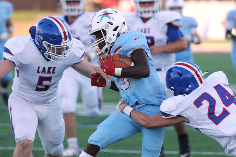 Ramhir Hawkins, center, of Alliance runs for big yardage before being taken down by Evan Brady, 5, and Dylan Snyder, 24, of Lake during their game at Alliance on Friday, August 19, 2022.