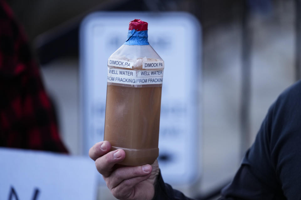 FILE - Craig Stevens holds a bottle of brown water as he speaks with members of the media outside the Susquehanna County Courthouse in Montrose, Pa., on Nov. 29, 2022. One of Pennsylvania's largest drillers will be allowed to extract natural gas from underneath a rural Pennsylvania community where it has been banned for a dozen years because of accusations it polluted the water supply, according to a settlement with state regulators obtained by The Associated Press on Thursday, Dec. 8, 2022. (AP Photo/Matt Rourke, File)