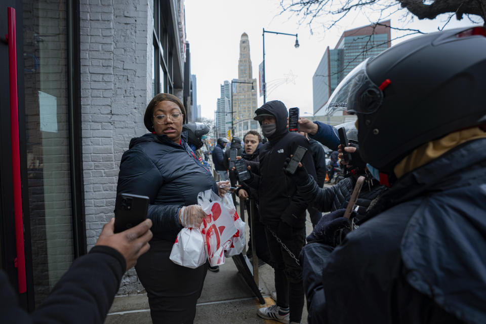 A Chick-fil-A employee distributes orders to delivery drivers on Thursday, Feb. 1, 2024, in New York. A wage law in New York City meant to protect food delivery workers is getting backlash from app companies like Uber, GrubHub and DoorDash, who have cut worker hours and made it more difficult to tip. (AP Photo/Peter K. Afriyie)