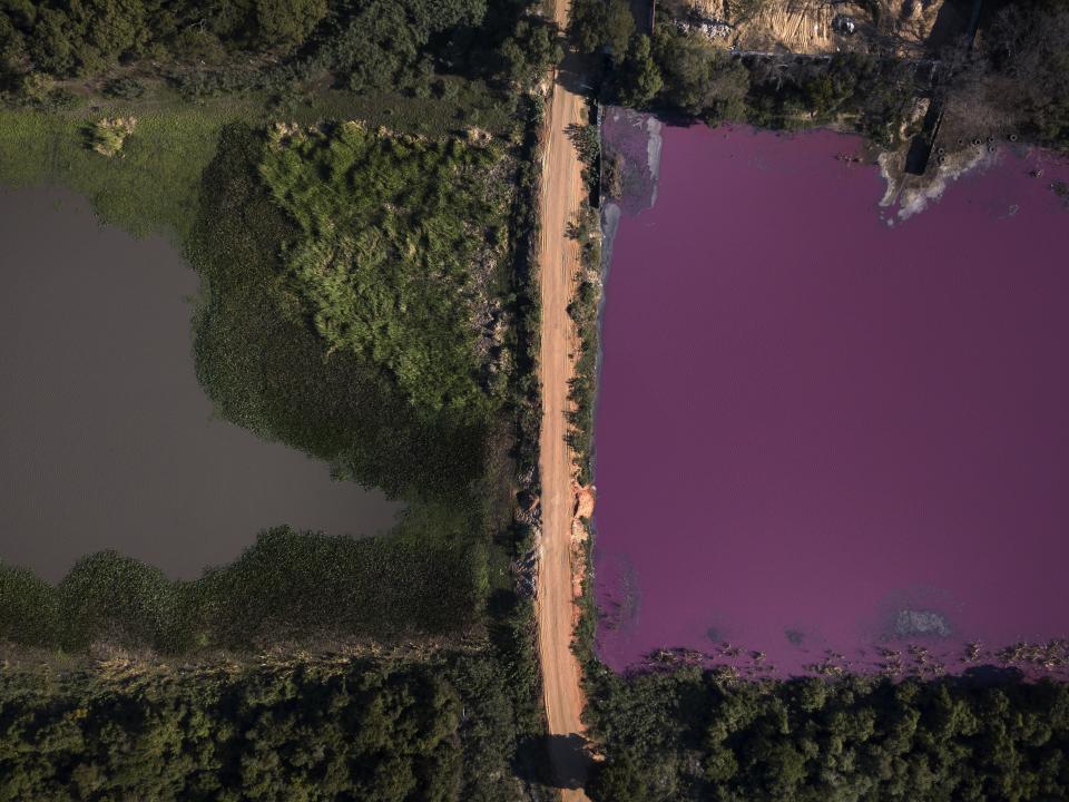 Un camino divide la laguna Cerro, donde el agua a la derecha tiene un color púrpura y la curtiduría Waltrading SA, se ubica en la orilla, arriba a la derecha en la imagen, en Limpio, Paraguay, el miércoles 5 de agosto de 2020. (AP Foto/Jorge Saenz)