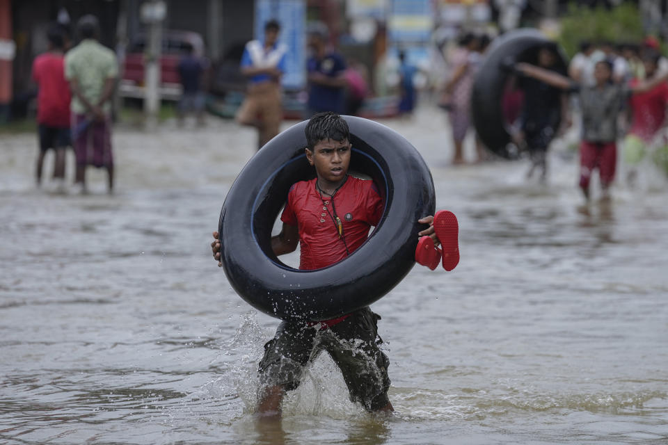 A boy carries an inflatable rubber tube as he wades through a flooded street in Biyagama, a suburb of Colombo, Sri Lanka, Monday, Jun. 3, 2023. Sri Lanka closed schools on Monday as heavy rains triggered floods and mudslides in many parts of the island nation, killing at least 10 people while six others have gone missing, officials said. (AP Photo/Eranga Jayawardena)