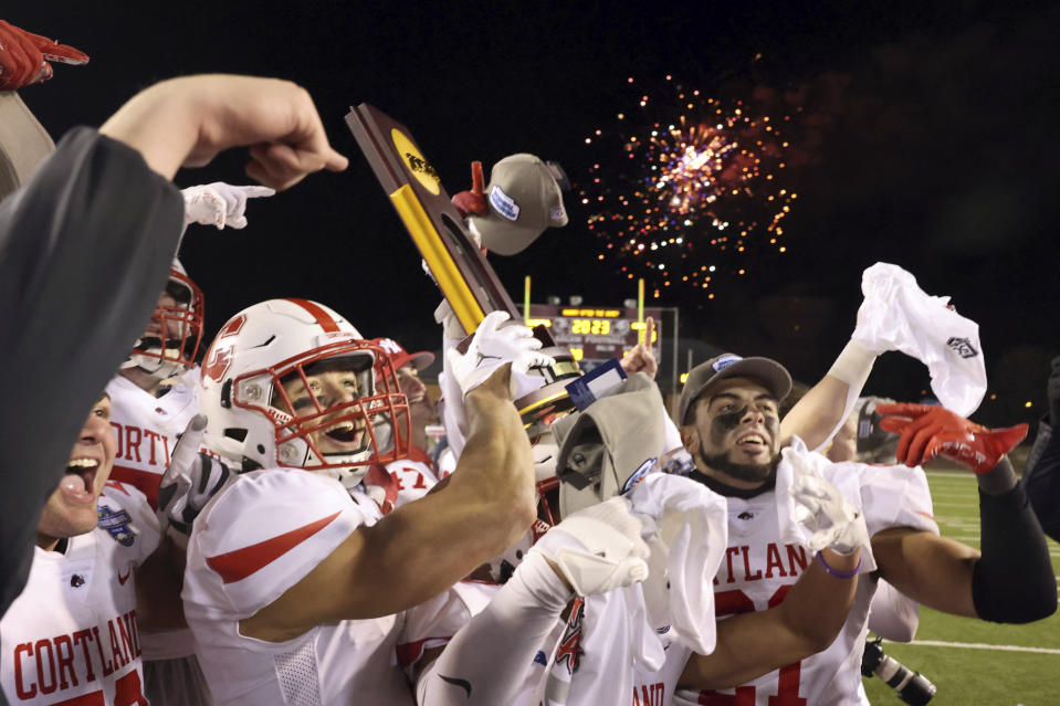 Cortland players celebrate with the trophy after a win over North Central in the Amos Alonzo Stagg Bowl NCAA Division III championship football game in Salem, Va., Friday Dec. 15, 2023. (Matt Gentry/The Roanoke Times via AP)