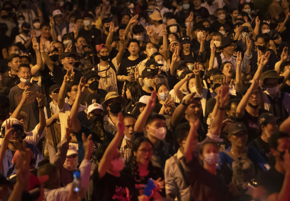 Pro-democracy protesters raise a three-finger salute, a sign of resistance, as they gather outside the Government House during a rally in Bangkok, Thailand, Wednesday, Oct. 14, 2020. Thousands of anti-government protesters gathered Wednesday for a rally being held on the anniversary of a 1973 popular uprising that led to the ousting of a military dictatorship, amid a heavy police presence and fear of clashes with political opponents. (AP Photo/Sakchai Lalit)