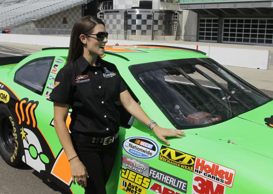 Race car driver Danica Patrick waits by a car she drove laps with journalist/television personality Katie Couric during a break in interviews at the Indianapolis Motor Speedway in Indianapolis, Tuesday, July 10, 2012. (AP Photo/Michael Conroy)