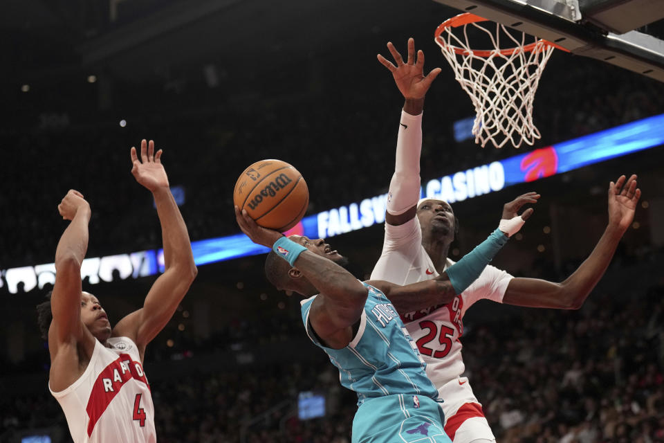 Charlotte Hornets guard Terry Rozier (3) drives to the net under pressure from Toronto Raptors forward Scottie Barnes (4) and teammate Chris Boucher (25) during the second half of an NBA basketball game in Toronto, Monday, Dec. 18, 2023. (Nathan Denette/The Canadian Press via AP)