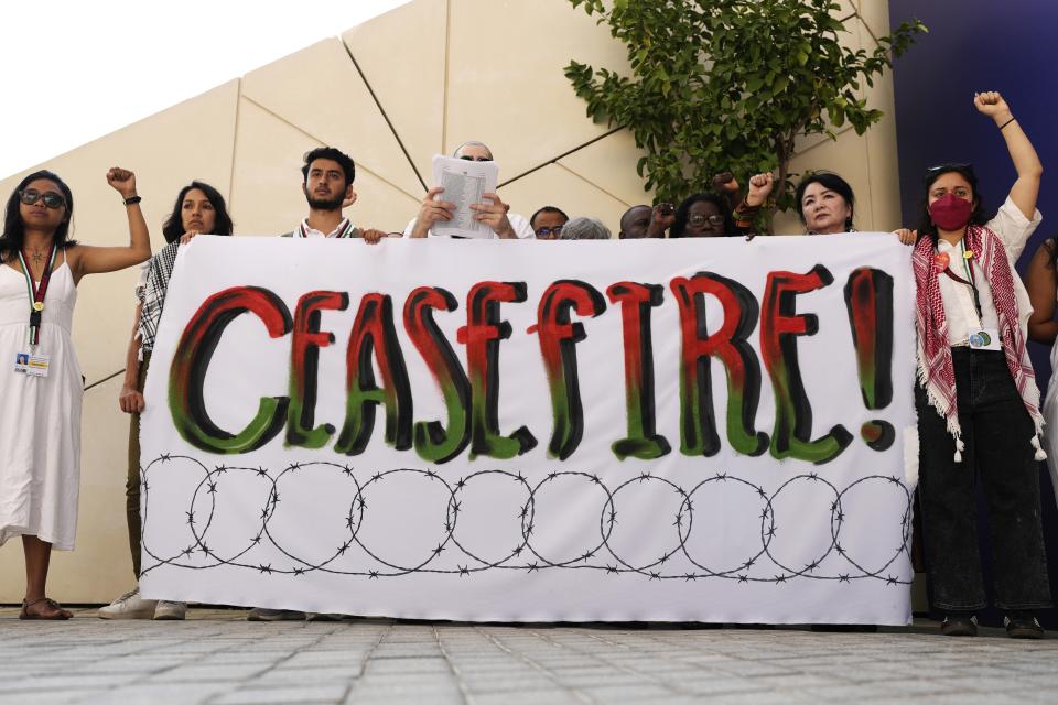 Demonstrators hold up their fists and a sign calling for a ceasefire in the Israel-Hamas war at the COP28 U.N. Climate Summit, Sunday, Dec. 3, 2023, in Dubai, United Arab Emirates. (AP Photo/Rafiq Maqbool)