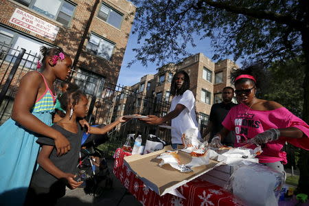 Mothers Against Senseless Killings (MASK) founder Tamar Manasseh (R) and Eric "Loco" Gilbert (3rd R) serve food to residents in the Englewood neighborhood of Chicago, Illinois, United States, August 4, 2015. REUTERS/Jim Young