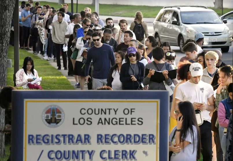 FILE - In this Nov. 6, 2018 file photo potential voters wait in long lines to register and vote at the Los Angeles County Registrar's office in Los Angeles.A pair of propositions on California's November ballot would expand voting rights in California - restoring the vote for parolees and allowing 17-year-olds to vote in primaries if they turn 18 before the general election. (AP Photo/Mark J. Terrill, File)