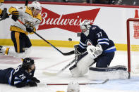 Winnipeg Jets goaltender Connor Hellebuyck (37) makes a save against Nashville Predators' Mikael Granlund (64) during the first period of NHL hockey game action in Winnipeg, Manitoba, Saturday, Oct. 23, 2021. (Fred Greenslade/The Canadian Press via AP)