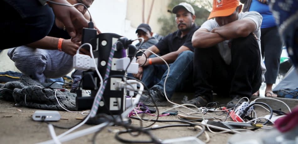 Members of the migrant caravan charge their phones.