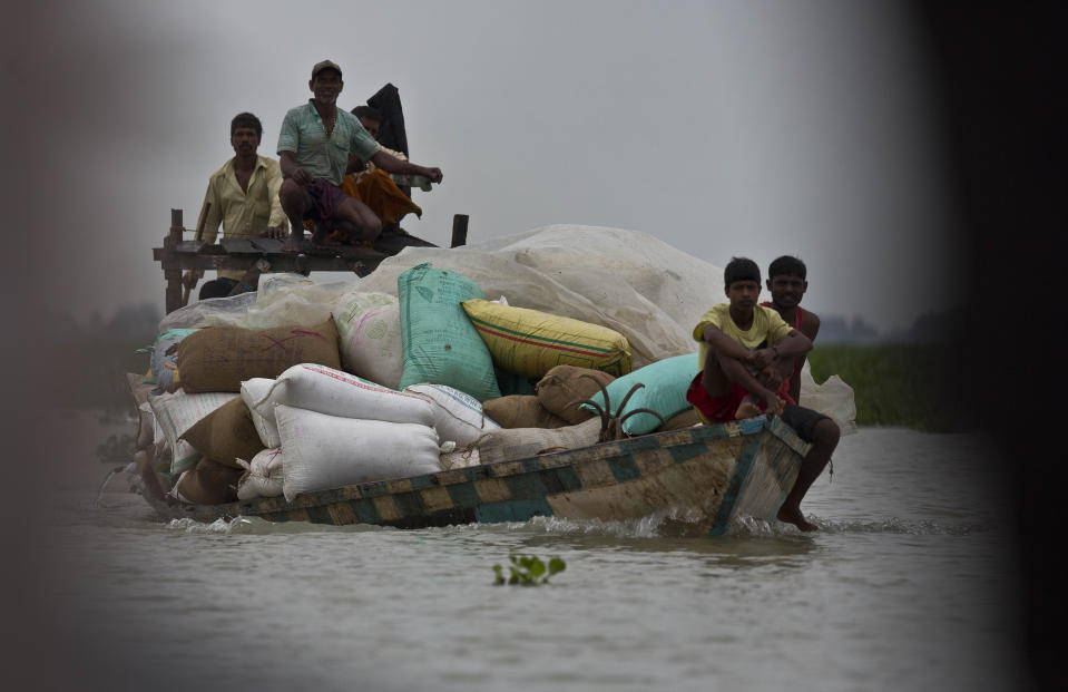 Indian villagers transport flood relief materials on a boat in Burgaon village, east of Gauhati, Assam, India, Monday, July 15, 2019. After causing flooding and landslides in Nepal, three rivers are overflowing in northeastern India and submerging parts of the region, affecting the lives of more than 2 million, officials said Monday. (AP Photo/Anupam Nath)