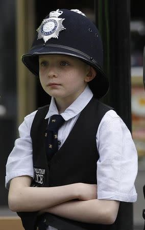 Nine year old Paul Warren, dressed as a police officer, stands in the street to watch the funeral processsion of PC Keith Palmer, the officer killed in the Westminster attack, in central London, Britain April 10, 2017. REUTERS/Peter Nicholls