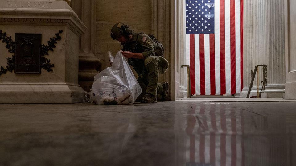 An ATF police officer cleans up debris and personal belongings strewn across the floor of the Rotunda in the early morning hours of Thursday, Jan. 7, 2021, after protesters stormed the Capitol in Washington, on Wednesday.