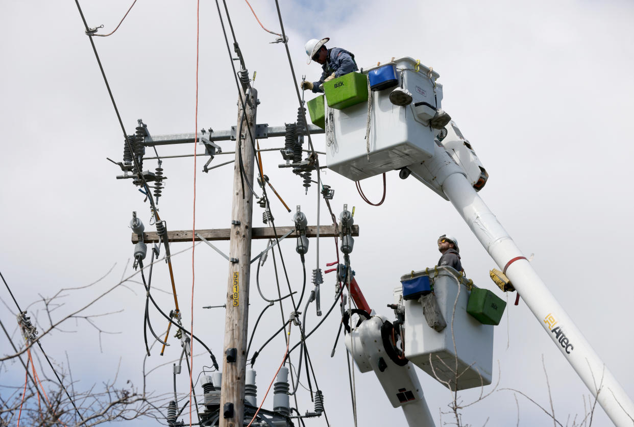 PG&E operators on two forklifts work on power lines.