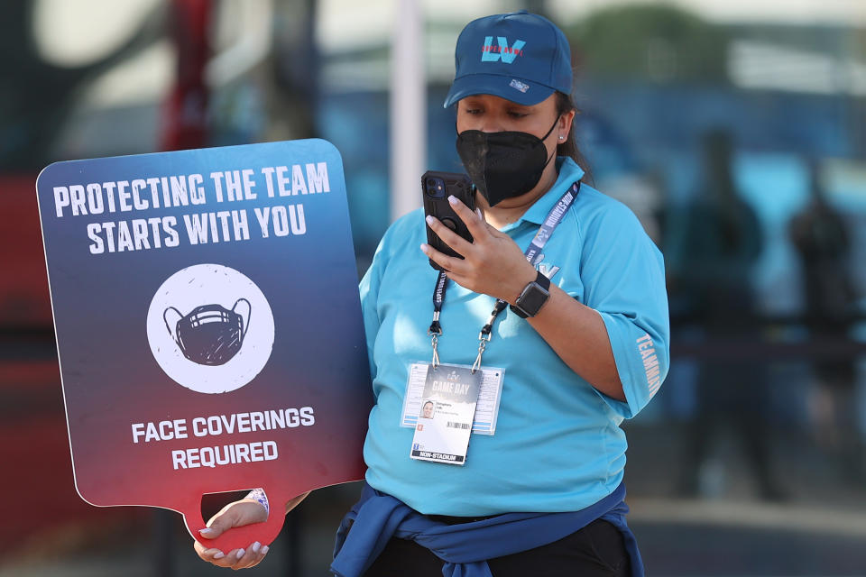 A worker holds a 'face coverings required' sign before Super Bowl LV between the Tampa Bay Buccaneers and the Kansas City Chiefs at Raymond James Stadium on February 07, 2021 in Tampa, Florida. (Photo by Patrick Smith/Getty Images)