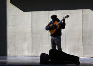 A lone street performer tunes his guitar on the deserted Hollywood Boulevard in Los Angeles on Tuesday, March 24, 2020. A tally by Johns Hopkins University on Tuesday found California coronavirus cases have topped 2,500, with at least 50 deaths. (AP Photo/Damian Dovarganes)