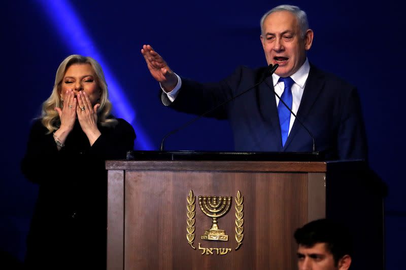 Israeli Prime Minister Benjamin Netanyahu stands next to his wife Sara as he speaks to supporters following the announcement of exit polls in Israel's election at his Likud party headquarters in Tel Aviv