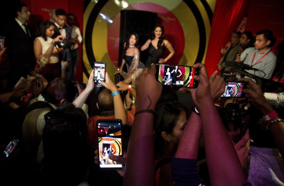 People raise their mobile phones to take photos and videos of Bollywood actress and former porn star Sunny Leone during the unveiling of her wax likeness at the Madame Tussauds museum in New Delhi, India, Tuesday, Sept. 18, 2018. The statue unveiled Tuesday represents the 37-year-old celebrity's acceptance by mainstream Indian society even as conservative Indian politicians condemn her porn-star past. (AP Photo/Anupam Nath)