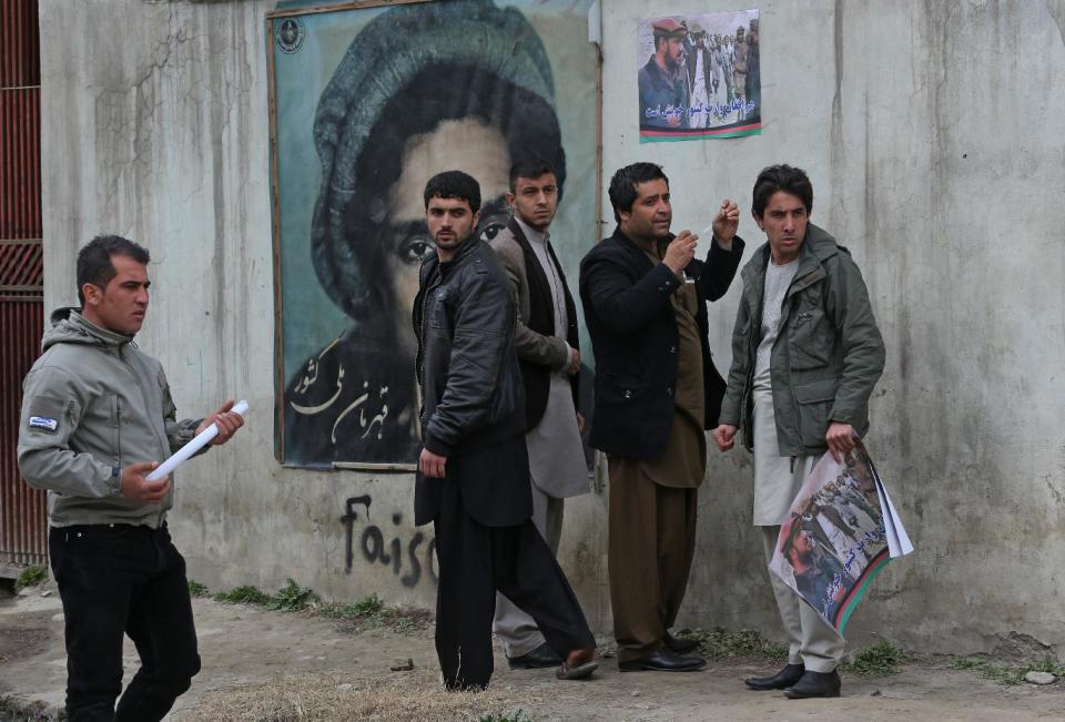 Supporters of Afghan Vice President Mohammad Qasim Fahim attach poster with his image on a wall in Kabul, Afghanistan, Sunday, March, 9 2014. Afghan Vice President Mohammad Qasim Fahim, a leading commander in the alliance that fought the Taliban who was later accused with other warlords of targeting civilian areas during the bloody conflict, died Sunday. He was 57. (AP Photo/Massoud Hossaini)