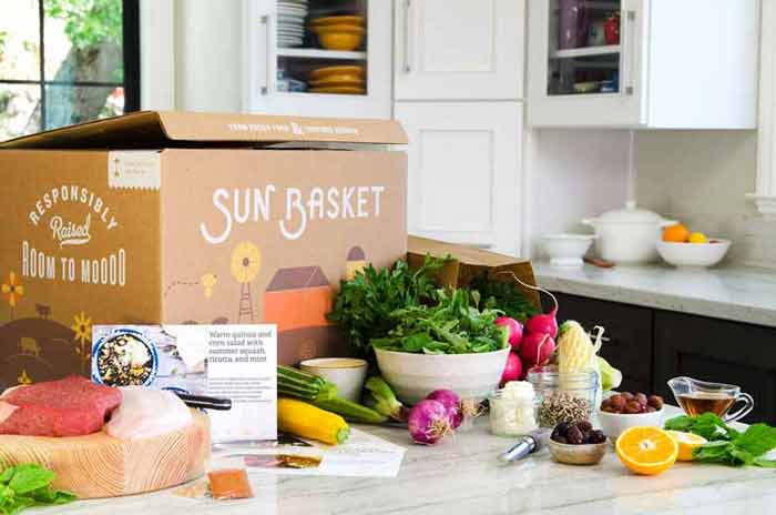 a kitchen counter with a box of food and bowls of vegetables laid out nicely next to a recipe card