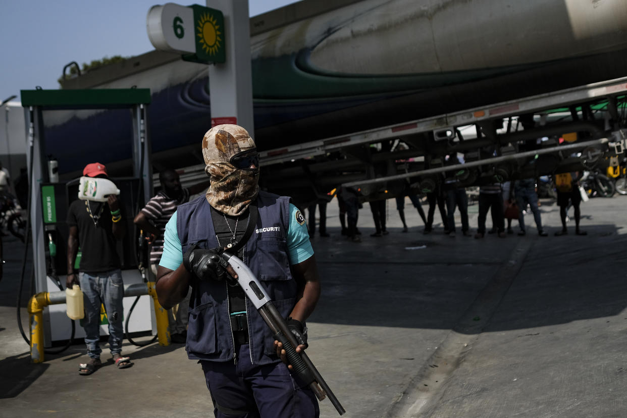 FILE - An armed security guard stands at a gas station as a tanker truck brings fuel to the gas station in Port-au-Prince, Haiti, Oct. 31, 2021. The U.S. government is urging U.S. citizens to leave Haiti given the country’s deepening insecurity and a severe lack of fuel that has affected hospitals, schools and banks. Gas stations remained closed on Thursday, Nov. 11, 2021, a day after the State Department issued its warning. (AP Photo/Matias Delacroix, File)