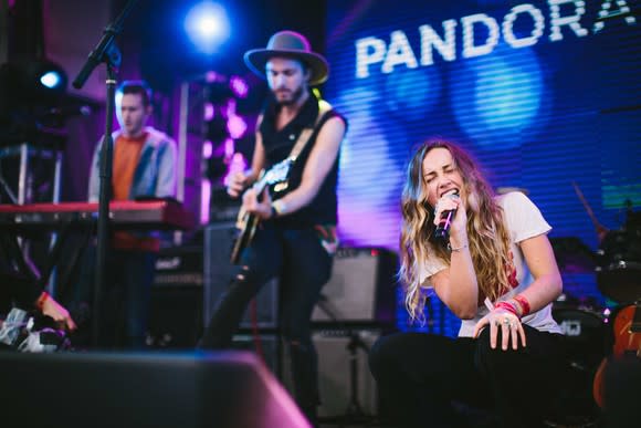 A singer, guitarist, and keyboardist performing a show with Pandora as a sponsor.