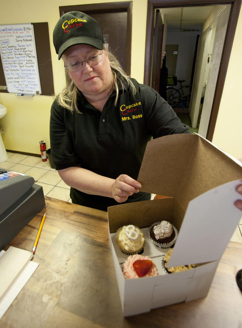 In this Wednesday, Aug. 1, 2012 photo, Eve Dobbins boxes up cupcakes at Cupcake Cache, a store run by she and her husband Michael, in Tampa, Fla. They opened Cupcake Cache in April. Money is so tight for the couple that he sold his golf clubs. Eve Dobbins recently took a college teaching job to supplement their income from the business, but both are convinced that with leases so cheap, they made the right move. (AP Photo/John Raoux)