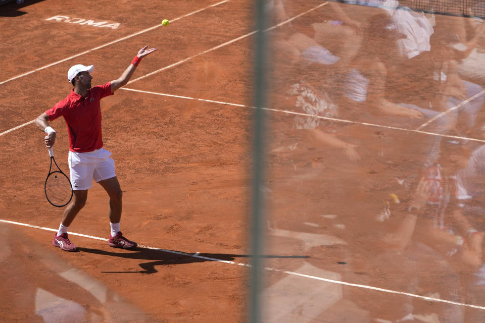 Serbia's Novak Djokovic serves the ball to Chile's Alejandro Tabilo as spectators are reflected in a glass dividers on the stands at the Italian Open tennis tournament in Rome, Sunday, May 12, 2024. (AP Photo/Alessandra Tarantino)