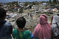 Indonesian women survey the damage suffered by Balaroa neighborhood which was flattened by Friday's earthquake in Balaroa neighborhood in Palu, Central Sulawesi, Indonesia Indonesia, Tuesday, Oct. 2, 2018. Home to hundreds of families, the neighborhood was once a patchwork of asphalted streets and tidy houses. Now it looks as if it was picked up and thrown back to earth with vicious force. Four days after the earthquake and tsunami hit the Indonesian city of Palu, this devastated neighborhood has received no government help and anger is simmering among its residents. (AP Photo/Dita Alangkara)